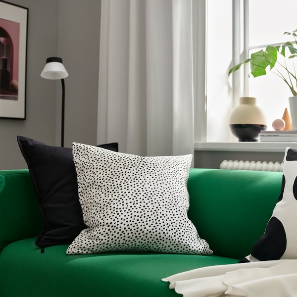 Grünes Sofa, gepunktetes Kissen, weiße Lampe, Vasen - Wohnzimmer.