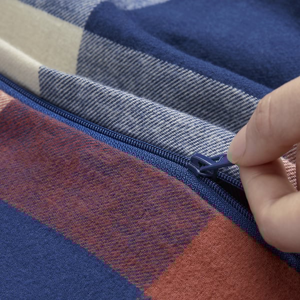 Handreißverschlüsse mit blauer und orangefarbener karierter Decke. Der Reißverschluss ist sichtbar und zeigt die Funktionalität.