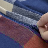 Handreißverschlüsse mit blauer und orangefarbener karierter Decke. Der Reißverschluss ist sichtbar und zeigt die Funktionalität.