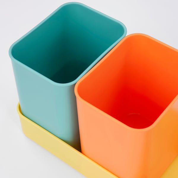 Drei bunte Plastikbehälter, die in einer gelben Schale verschachtelt sind. Lebendig, robust und organisiert.