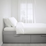 BRIMNES weißes Bett mit großen grauen Schubladen, klaren Linien und viel Stauraum.