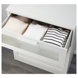 Öffnen Sie die IKEA BRIMNES-Schublade mit gefalteter Kleidung: Pullover, Hemd, gestreiftes Hemd.