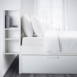 Bett mit offenen Ablagefächern, zwei große Kissen, weiß.