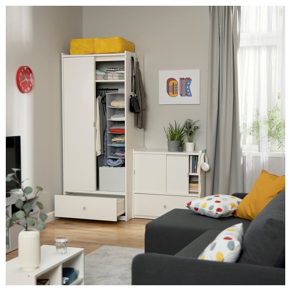 Modernes Wohnzimmer mit weißem Stauraum, Schiebetüren, gelber Platte, grauem Sofa und Pflanzen.