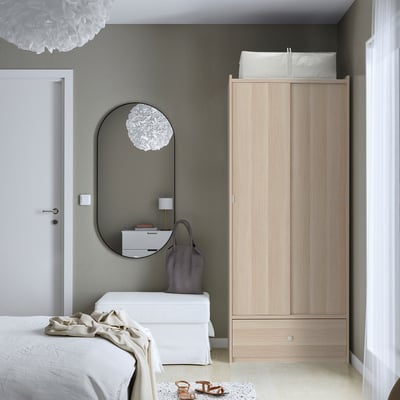 Minimalistisches Schlafzimmer mit BRUKSVARA-Kleiderschrank aus Eiche, Schiebetüren, ruhigen grauen Wänden.