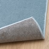 Ecke aus weichem, leichtem blauem Teppich auf Holzboden.