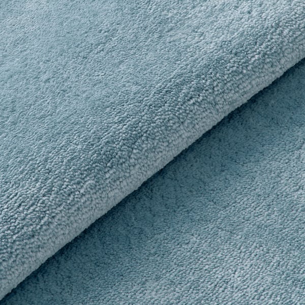 Weiche, überlappende Teppiche in hellen Blautönen, die sich durch eine weiche Textur und hochwertiges Material auszeichnen.