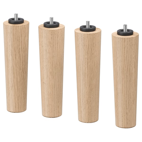 Vier helle Holzbeine mit schwarzen Metallaufsätzen, die in einer Reihe angeordnet sind.
