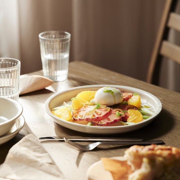 Beige Suppenschüssel mit Orangen und Ölen auf Holztisch, fertig zum Essen.