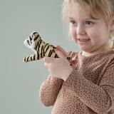 Ein junges Mädchen hält einen kleinen Spielzeugtiger in der Hand, beide lächeln. Der Tiger besteht aus weichem, recyceltem Material, das sich perfekt zum Trosten und Spielen eignet.