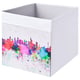 Weiße DRÖNA-Aufbewahrungsbox mit farbenfrohem Stadt-Skyline-Design, quadratischer Form und Netzplatte.