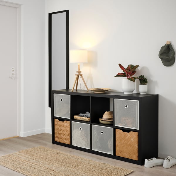 Kallax Regal mit DRÖNJÖNS Boxen. Lampe, Pflanzen, Hut und Turnschuhe ausgestellt.