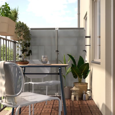 Moderner Balkon mit weißem Metalltisch und Stühlen, umgeben von üppigen grünen Pflanzen, die einen ruhigen Außenbereich schaffen.