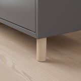 Moderner Aufbewahrungsschrank mit elegantem grauem Finish und robusten Holzbeinen.