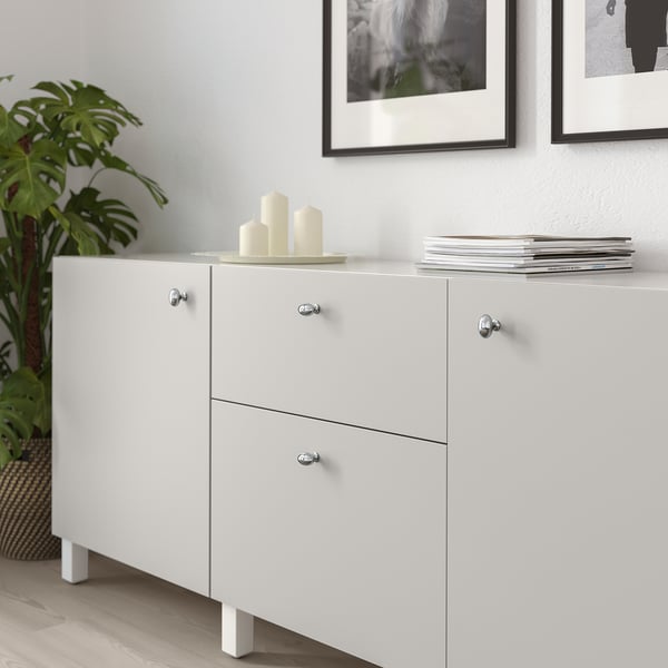 Weißer Schrank mit Knöpfen; Kerzen und Pflanze obendrauf; gerahmte Kunst dahinter.