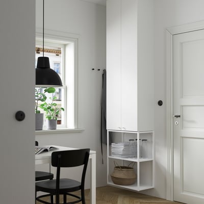 Moderne Büroecke mit weißem ENHET-Schrank und Schreibtisch. Schwarzer Stuhl, Hängelampe und graue Vorhänge. Pflanze auf der Fensterbank. Aufgeräumtes und minimalistisches Design.