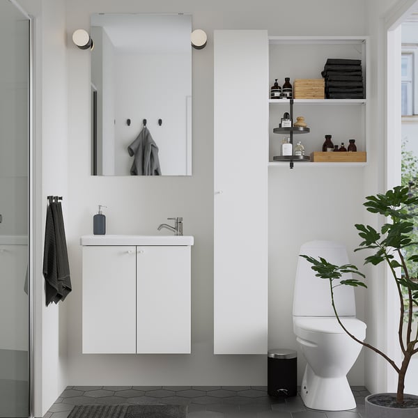 Modernes, minimalistisches Badezimmer mit weißem Waschtisch, Spiegel und schwarzen Akzenten. Die Topfpflanze sorgt für Grün.