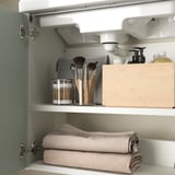 Offener Badezimmerschrank mit Handtüchern und Schönheitsprodukten.