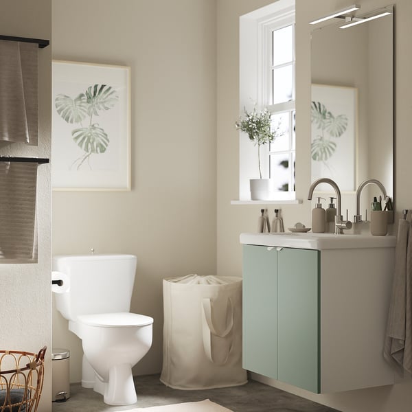 Dieses Bild zeigt ein modernes Badezimmer mit einem grau-grünen ENHET-Schrank, einer weißen Toilette und einem schwimmenden Waschbeckenschrank mit einer großen weißen Arbeitsplatte.
