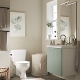 Dieses Bild zeigt ein modernes Badezimmer mit einem grau-grünen ENHET-Schrank, einer weißen Toilette und einem schwimmenden Waschbeckenschrank mit einer großen weißen Arbeitsplatte.