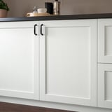 Weißer Küchenschrank mit dunklem Griff, Holzboden, Arbeitsplatte mit Gegenständen. Teil der ENKÖPING-Serie, beständig gegen Feuchtigkeit und Flecken.