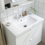 Modernes Waschbecken mit verchromtem Wasserhahn, Seifenspender, Handtuch, Pflanze und wassersparendem Belüfter.