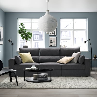 Modernes Wohnzimmer mit grauem Sofa, Teppich und großen Fenstern. Geräumiges Sofa mit Kissen und elegantem Couchtisch.