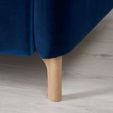 Modernes, tiefblaues Sofa mit verstellbaren Kopfstützen und Holzbeinen auf hellem Holzboden.