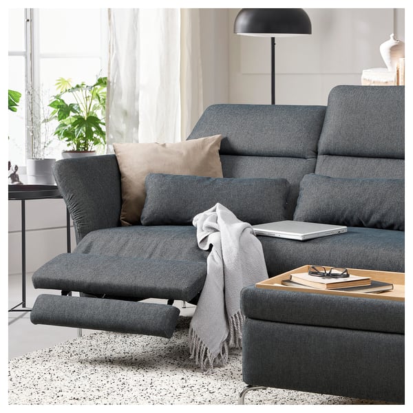 Modernes Wohnzimmer mit grauem FAMMARP-Sofa, Kissen, Lampe, Laptop und Büchern.