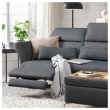 Modernes Wohnzimmer mit grauem FAMMARP-Sofa, Kissen, Lampe, Laptop und Büchern.