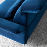 Tiefblaues Samtsofa mit weichen Kissen, das hochwertiges Design und Komfort zeigt.