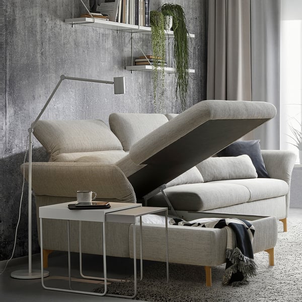 Modernes graues FAMMARP-Sofa mit verstellbaren Kopfstützen und Rückenlehnen, Holzbeinen und einem kleinen Beistelltisch mit Tasse und Fernbedienung.