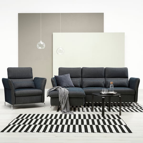 Modernes schwarzes Möbelset: dunkelgraues Sofa, Stuhl und Couchtisch auf schwarz-weiß gestreiftem Teppich.