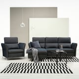 Modernes schwarzes Möbelset: dunkelgraues Sofa, Stuhl und Couchtisch auf schwarz-weiß gestreiftem Teppich.
