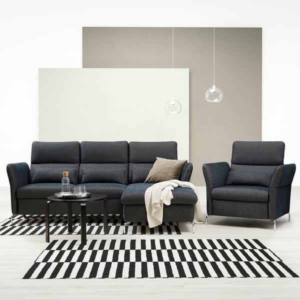 Modernes Wohnzimmer mit dunkelgrauem FAMMARP-Sofa und -Stuhl, schwarz-weiß gestreiftem Teppich und Kugel-Pendelleuchten.