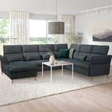 Modernes Wohnzimmer mit großem grauem FAMMARP-Sofa, weißem Couchtisch und großen Fenstern. Das Sofa bietet Platz für mehrere Personen.