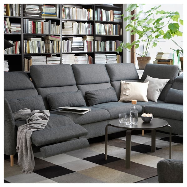 Modernes Wohnzimmer mit FAMMARP-Sofa, schwarzem Couchtisch, Bücherregal und Pflanze.