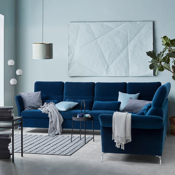 Gemütliches FAMMARP-Sektionssofa aus blauem Samt mit verstellbaren Kissen und moderner Wandkunst in einem trendigen Wohnraum.