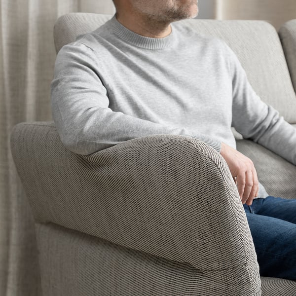 Mann sitzt auf grauem FAMMARP-Sofa und trägt einen hellgrauen Pullover.