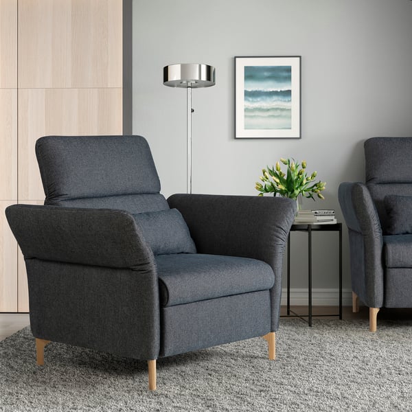 Modernes Wohnzimmer mit FAMMARP-Sesseln, Beistelltisch, Blumenvase, Küstengemälde und Stehlampe.