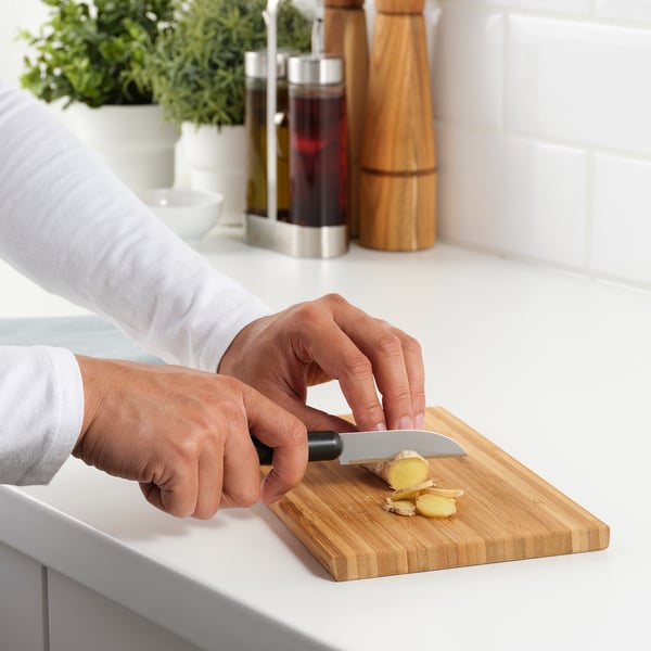 Hände schneiden Ingwer auf einem Holzschneidebrett mit scharfem FÖRDUBBLA-Messer.