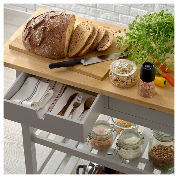 Grauer FÖRHÖJA Küchenwagen mit Holzplatte für Brot, Messer, Nüsse, Pfeffer. Schublade mit Tüchern und Besteck, Regale mit Lebensmittelgläsern.