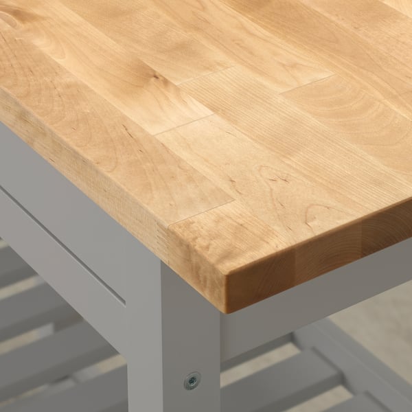 Nahaufnahme einer glatten, gut gearbeiteten Tischplatte aus hellem Holz auf robusten weißen Metallbeinen.