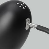 Nahaufnahme einer verstellbaren schwarzen Lampe mit Metallgelenk und Schrauben. Glatte Oberfläche, robuste Bauweise.