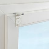Die weiße, bohrfreie Halterung wird an der Ecke des Fensterrahmens befestigt und hält die Rollobeschläge.