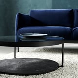 Modernes Wohnzimmer: blaues Sofa, schwarzer runder Couchtisch mit Glasplatte.