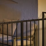 Metallgeländer mit bunten Lichterketten. Die Leuchten verfügen über einen eingebauten Timer und sind batteriebetrieben.