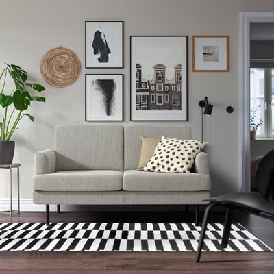 Modernes Wohnzimmer: GRILLSTORP hellgraues Sofa mit Kissen, schwarz-weißer Teppich, Kunstwand, Pflanze. Bequem und stilvoll, kompakte Größe.