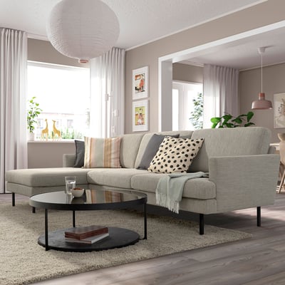 Das graue Sofa GRILLSTORP dominiert dieses gemütliche Wohnzimmer mit seinem großen, einladenden Design, begleitet von einem runden Couchtisch und einem Plüschteppich.