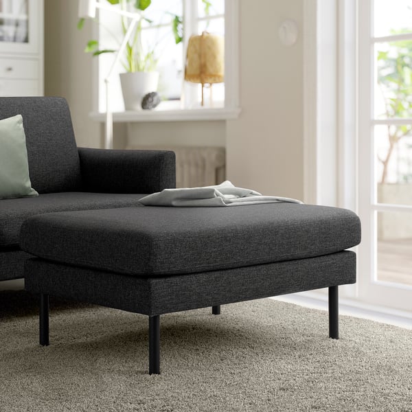 Dunkelgraues GRILLSTORP Sofa & kleiner Fußhocker im hellen Wohnzimmer.
